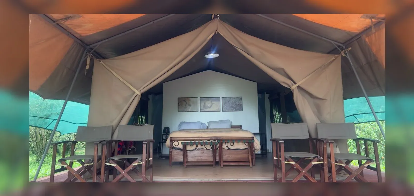 Exterior of a canvas safari tent with two lounge chairs on a wooden deck at Kaboso Safari Camp.