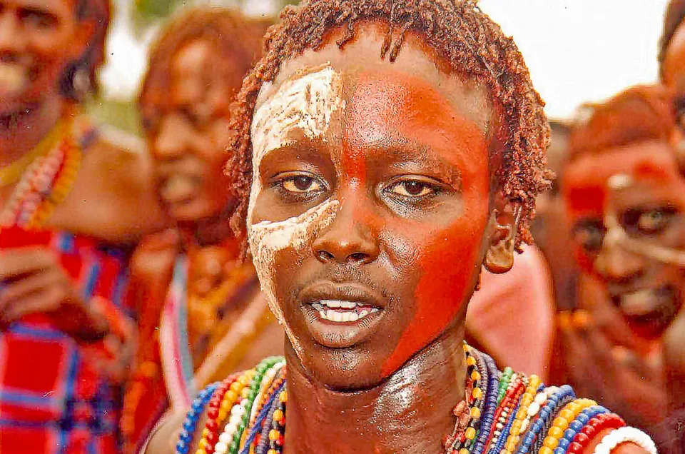 Close-up portrait of a person with face paint and layered bead necklaces.